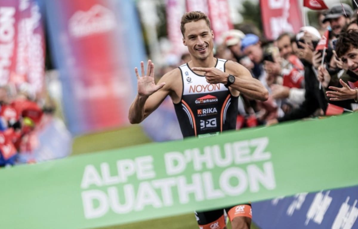 Endurance athlete celebrating victory at mountain duathlon finish line in French Alps