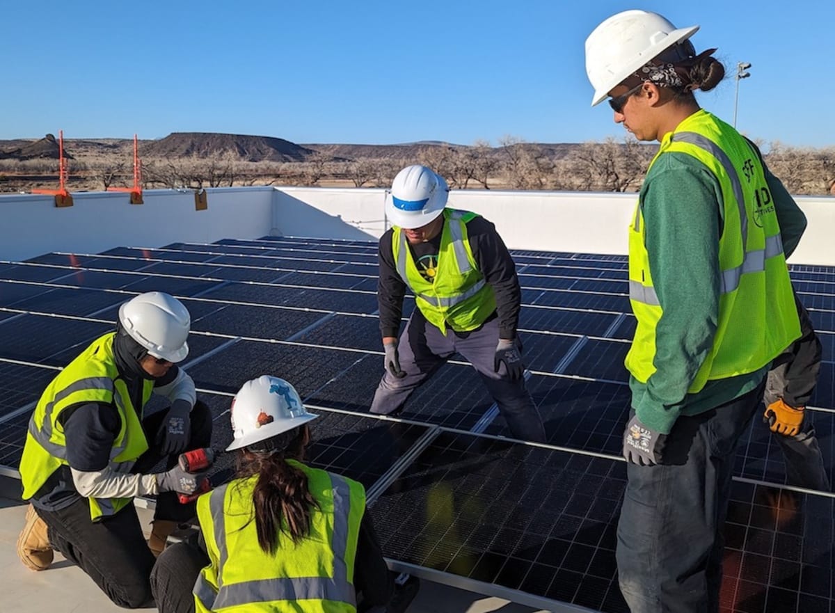Native American worker installing solar panels on rooftop during hands-on training session