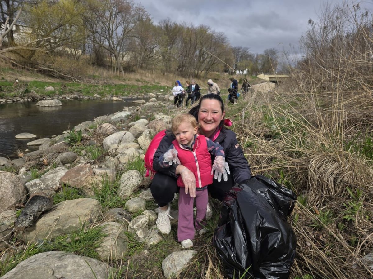Volunteers in matching shirts collecting trash and debris along a Milwaukee area riverbank
