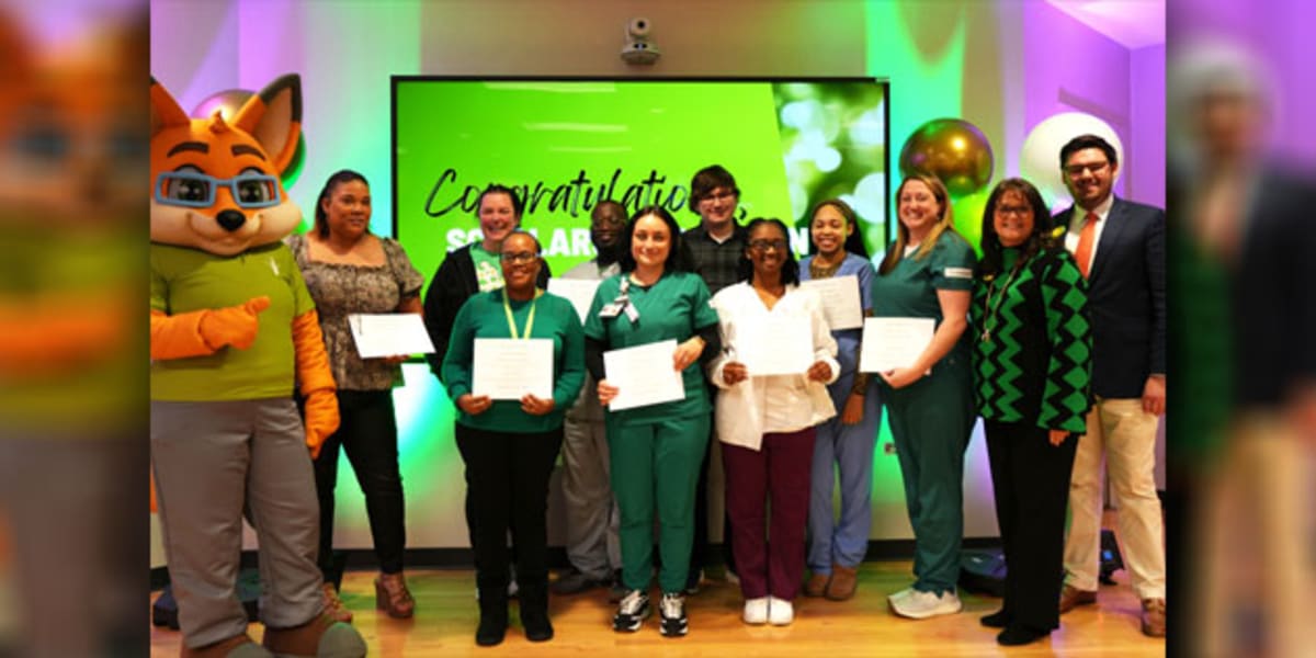 Nine scholarship recipients standing with Wiregrass mascot and college president holding awards at ceremony