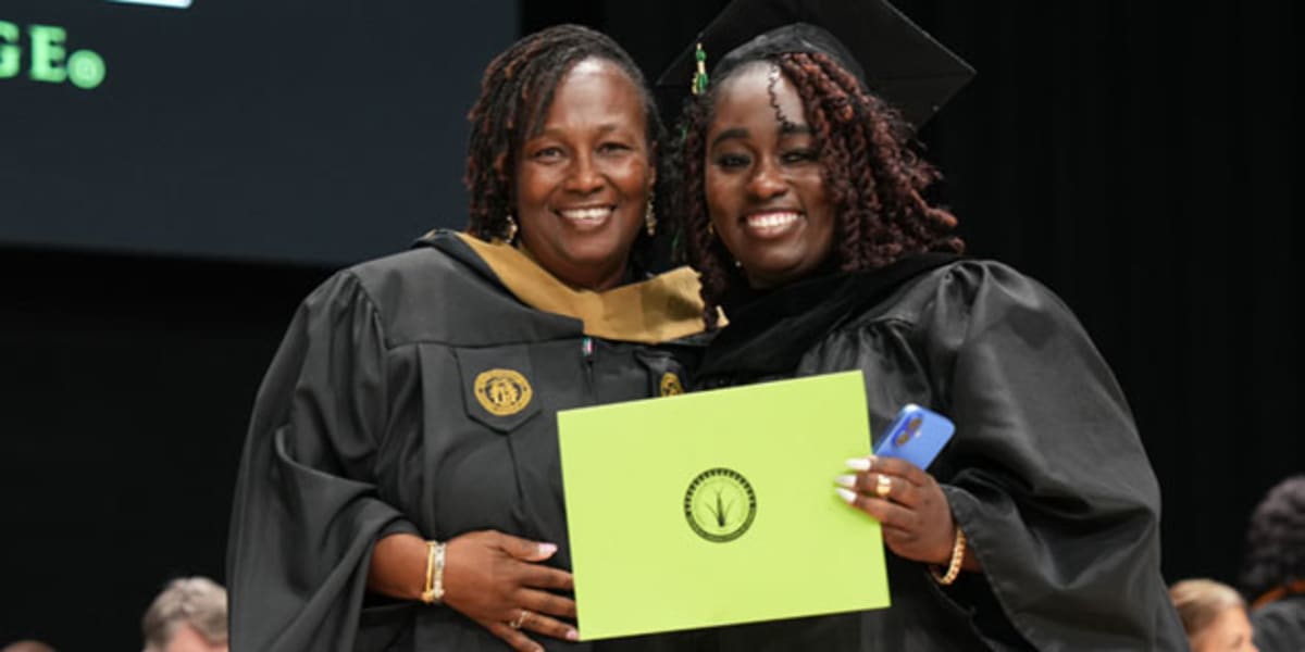 Campus Director Paulette Brown standing with daughter Chrissa Davis in nursing graduation cap and gown