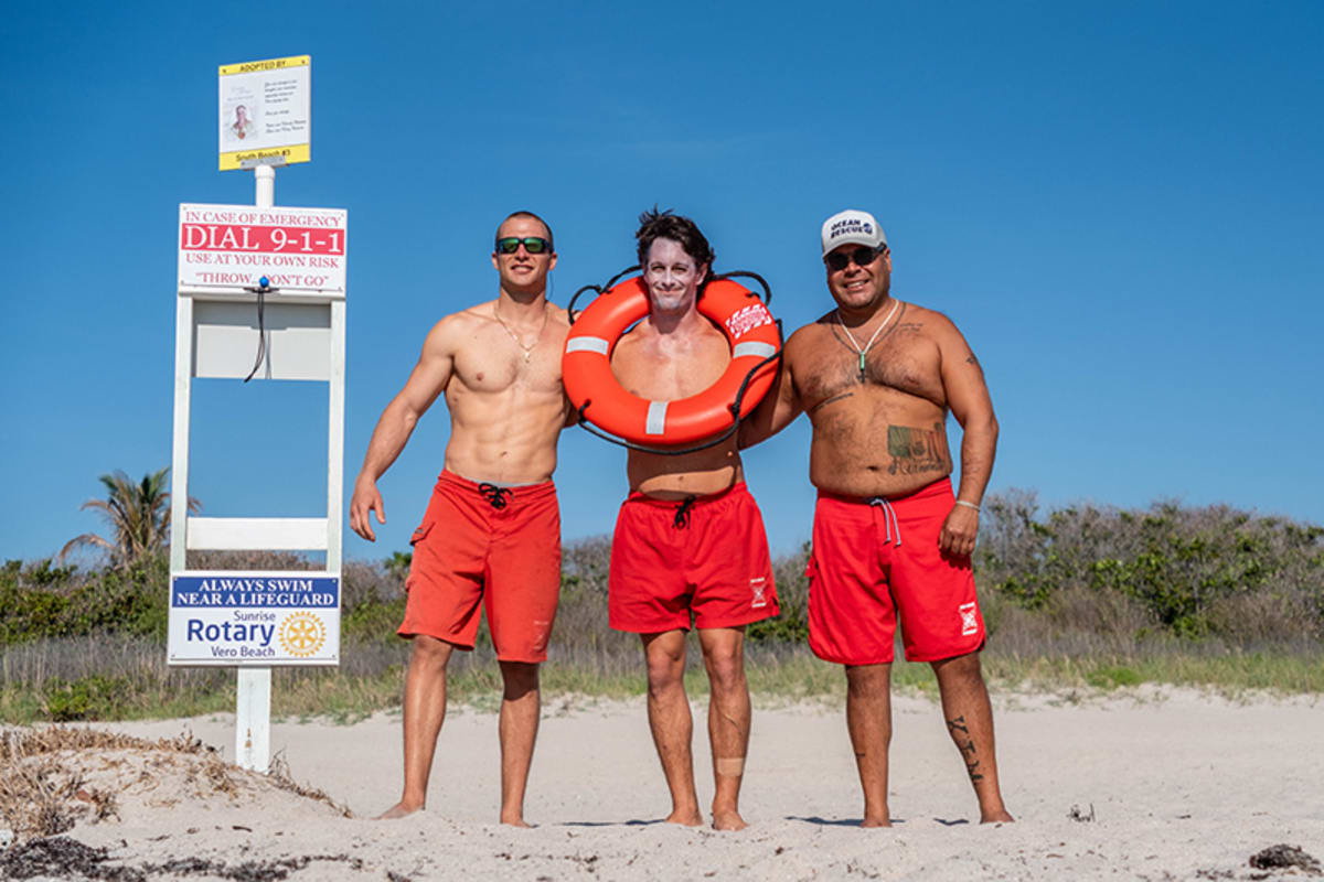 Orange life ring rescue station on beach with ocean waves in background