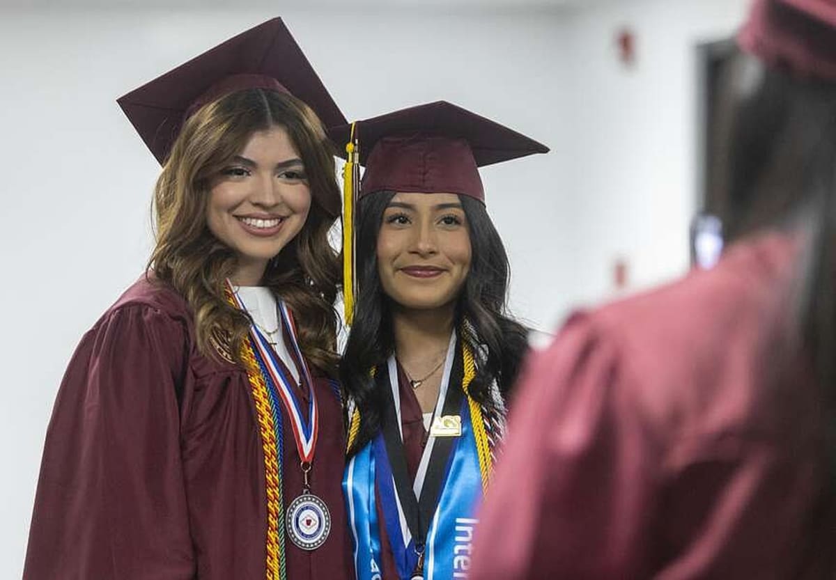 Rogers Academy graduates in caps and gowns tossing graduation caps in celebration