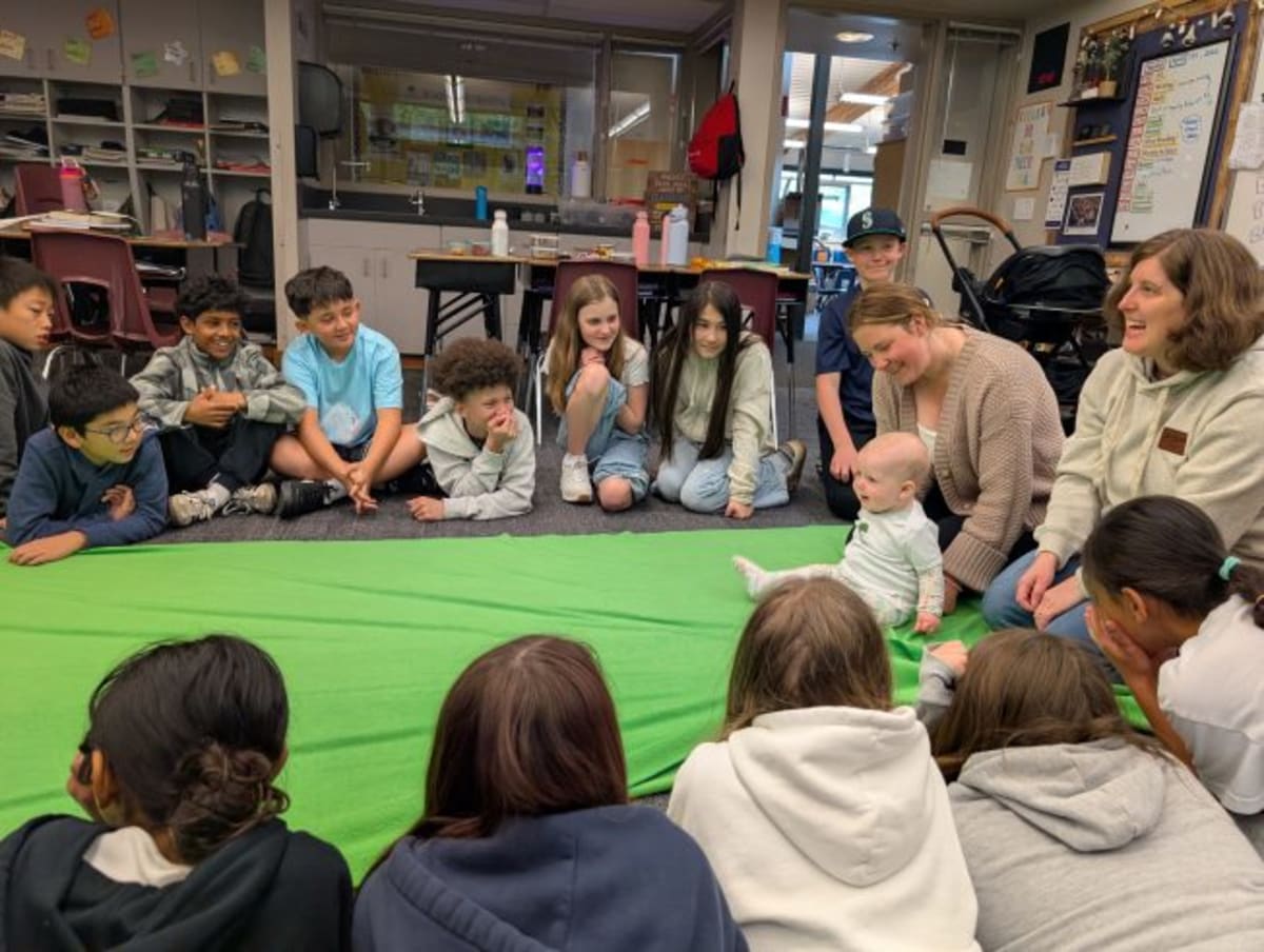Young elementary students sitting in circle observing baby and parent during Roots of Empathy classroom session