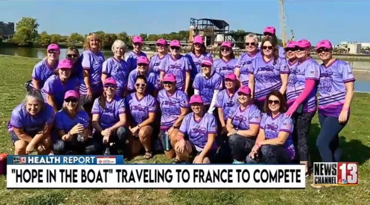 Breast cancer survivor dragon boat team paddling together in synchronized motion on water