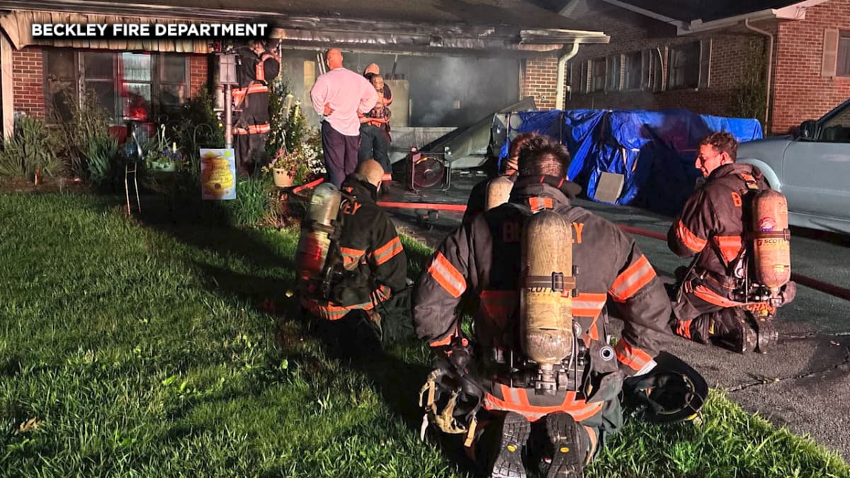 Firefighter in protective gear gently holds rescued dog after early morning house fire