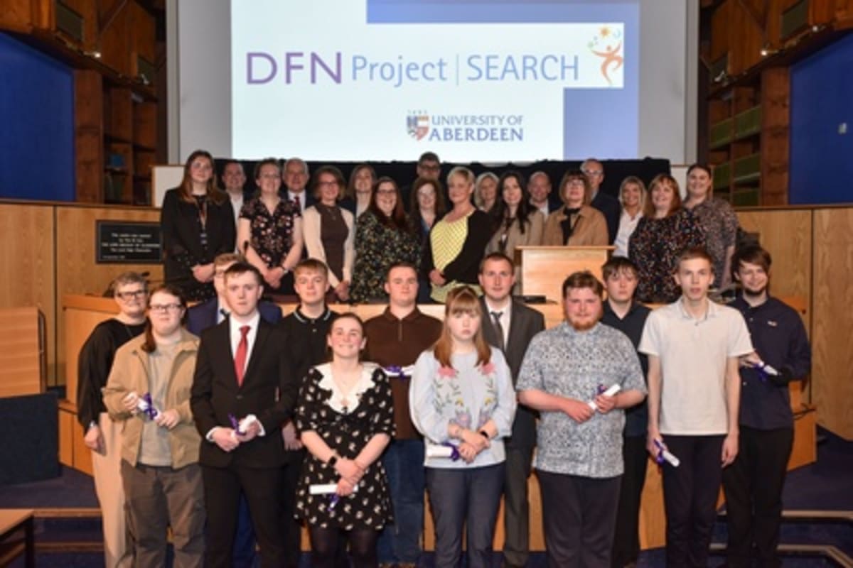 Young graduates with learning disabilities celebrating at ceremony with certificates in university setting