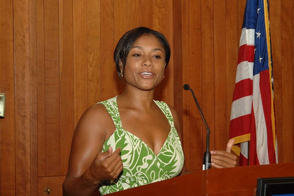 Dominique Dawes smiling in gymnastics attire, Olympic gold medalist and academy founder
