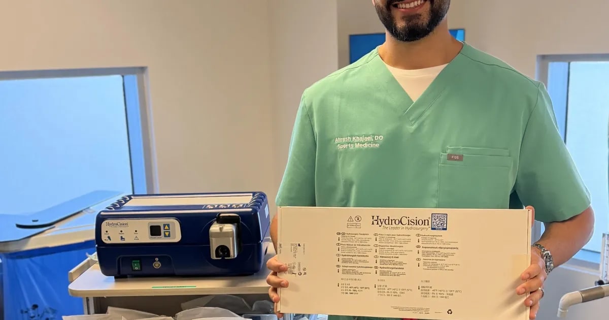 Doctor using ultrasound equipment to perform minimally invasive tendon treatment on patient