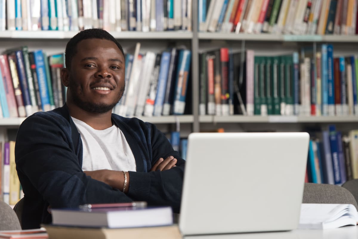 Student studying at desk with books and laptop in Alaska classroom setting