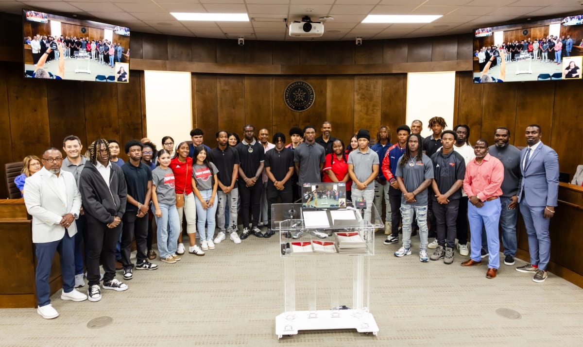 Students holding certificates and trophies at Aldine ISD board meeting celebrating academic and athletic achievements