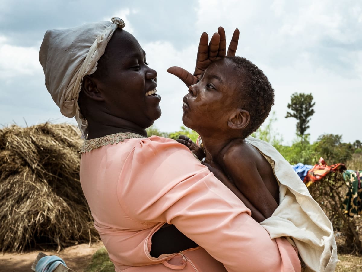 ** Young mother Martha Apolot holds her son Aaron inside their small home in rural Uganda