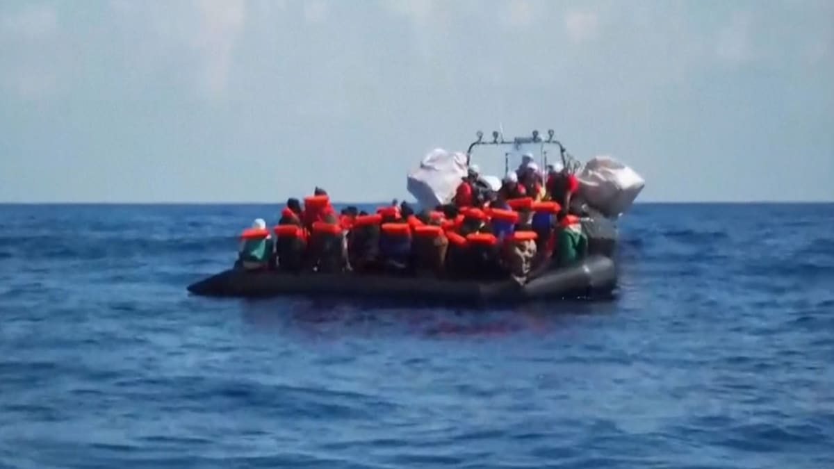 Rescue workers helping migrants board humanitarian vessel in Mediterranean Sea waters
