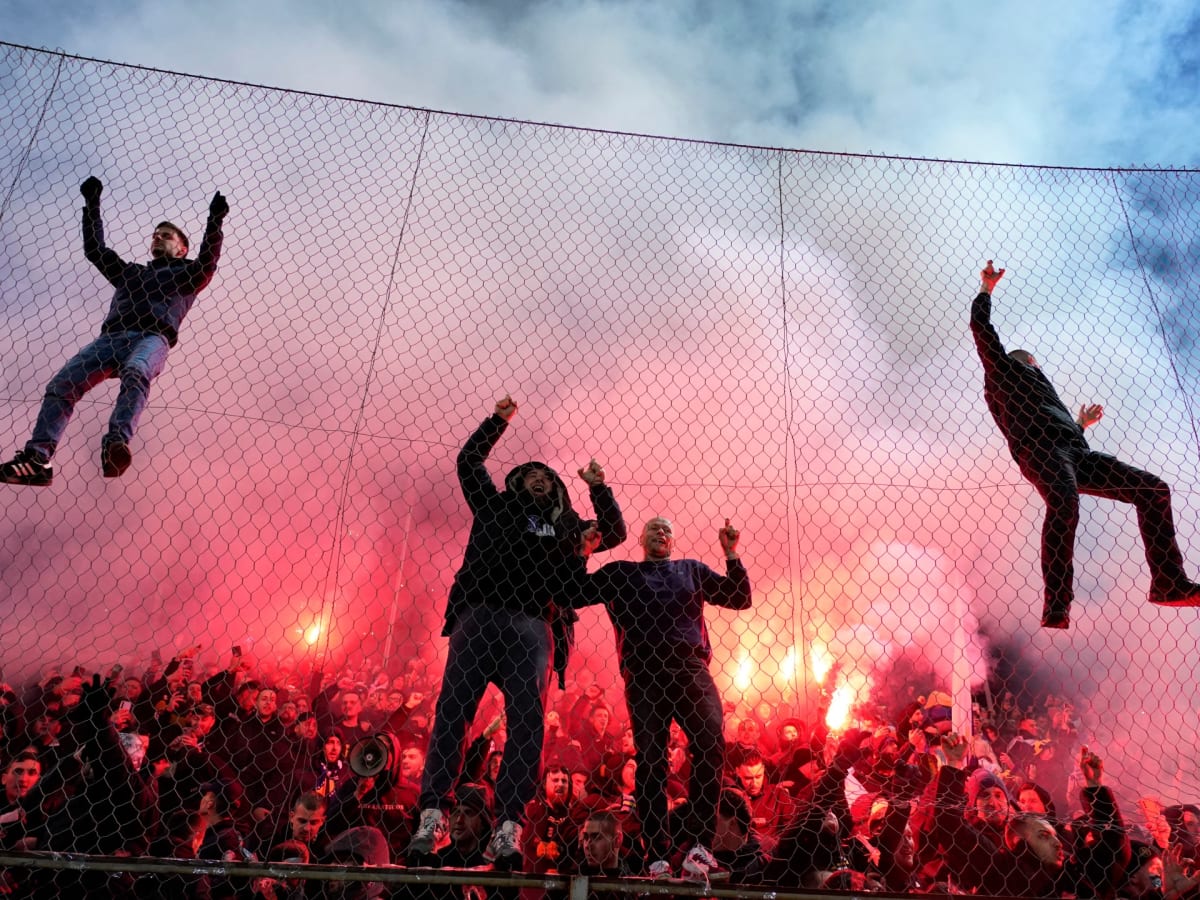 ** Bosnian football fans celebrate with flags and flares at Bilino Polje Stadium in Zenica