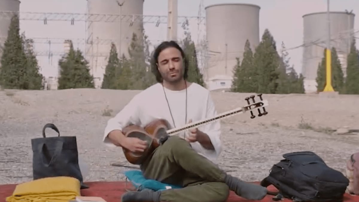 ** Iranian musician Ali Ghamsari performing with instrument outside Damavand power station in peaceful protest