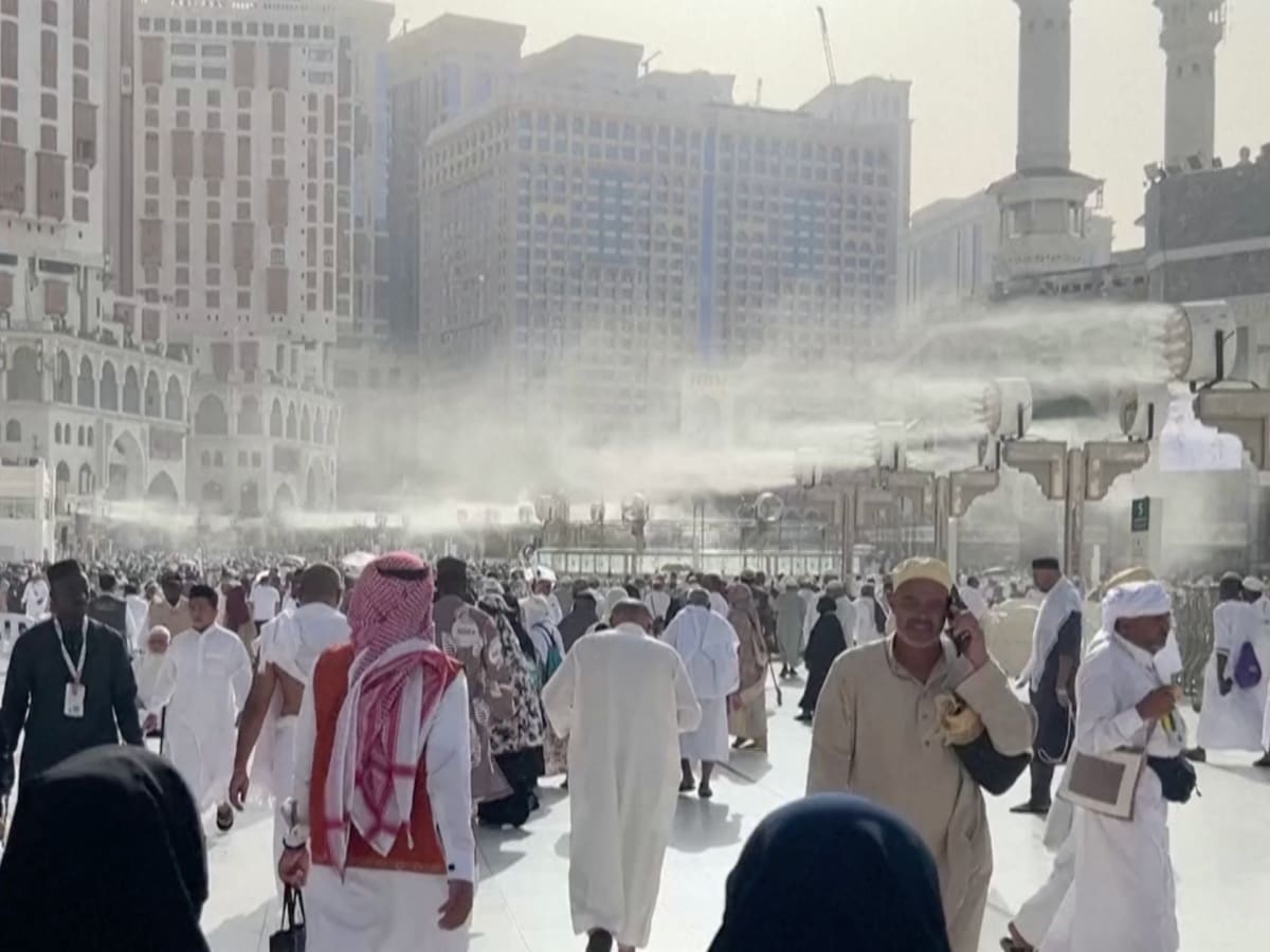 Muslim pilgrims sheltering under umbrellas and shade structures in Mecca during hot weather