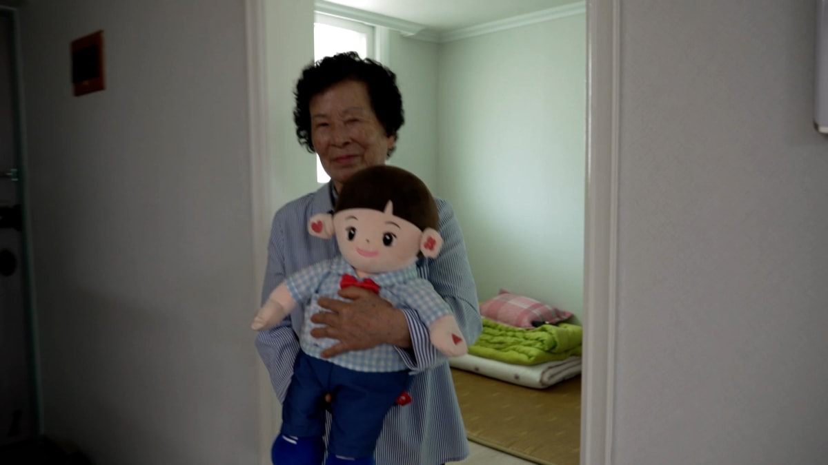 Elderly person interacting with small AI companion robot in South Korean home
