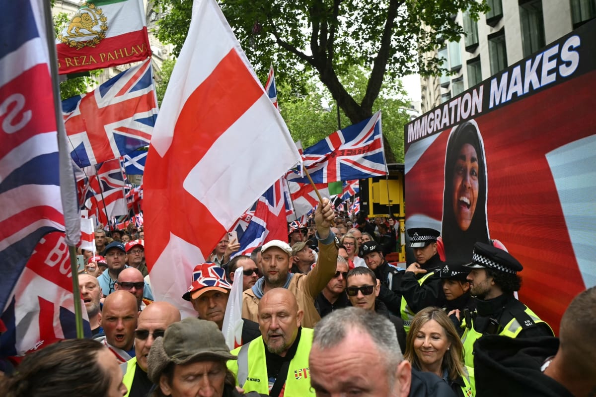 Large display screen showing pro-immigration messages at crowded political rally in United Kingdom