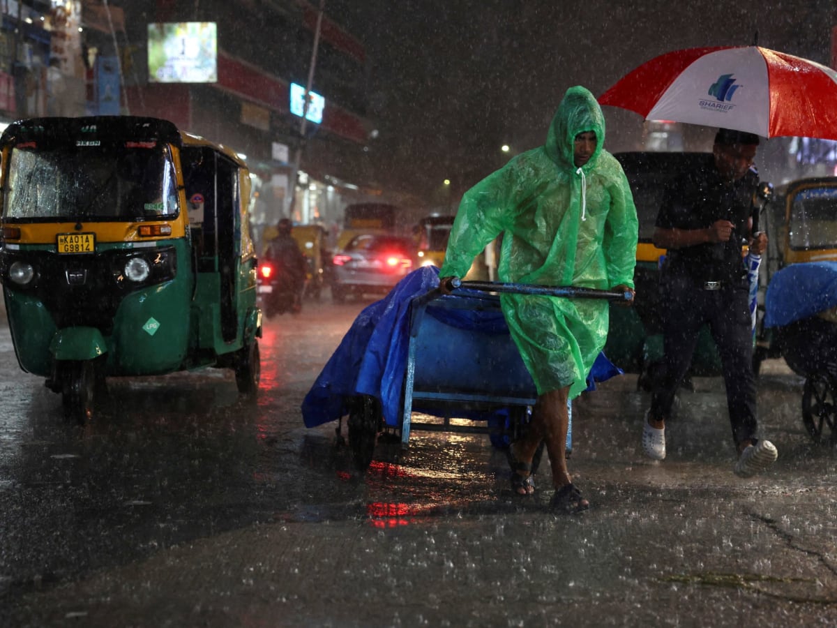 Person pulling cart through monsoon rain on wet street in Bengaluru, India