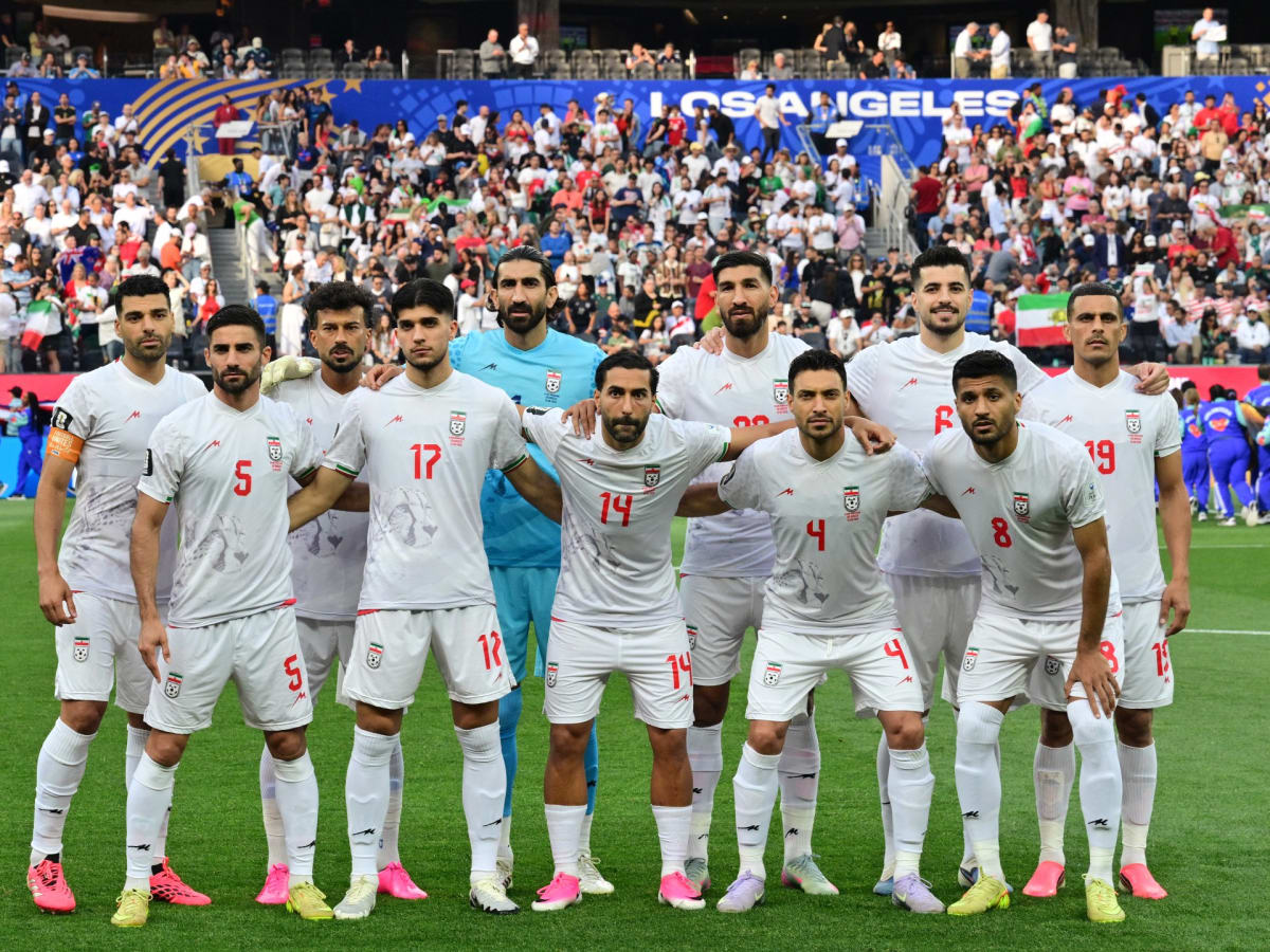 ** Iranian soccer fans celebrating together in stadium stands waving flags during World Cup match