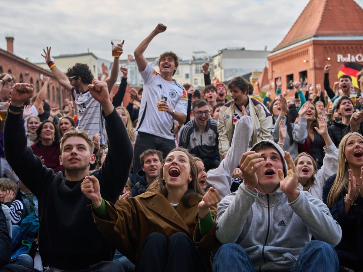 Diverse crowds of World Cup fans celebrating together in outdoor public viewing spaces worldwide