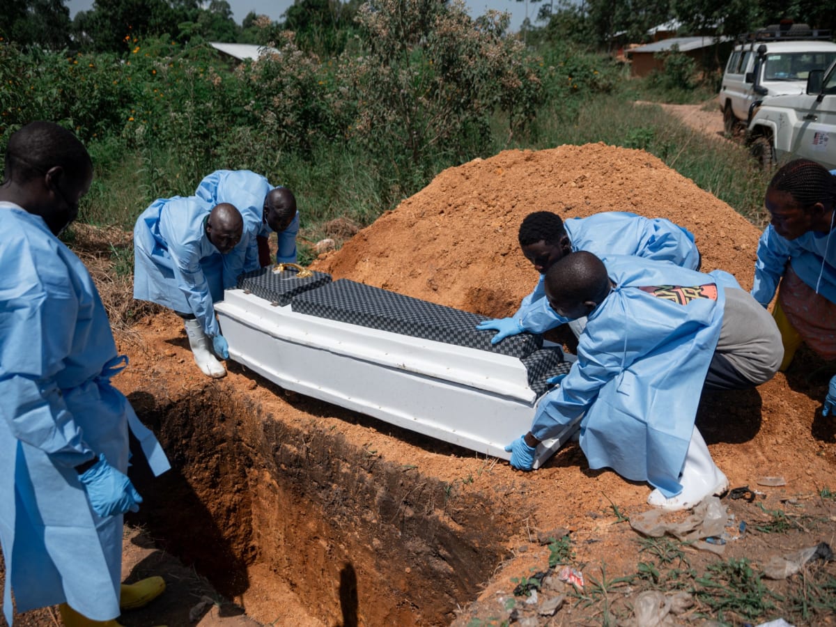 Health workers in protective gear screen travelers at Uganda-Congo border crossing during Ebola response