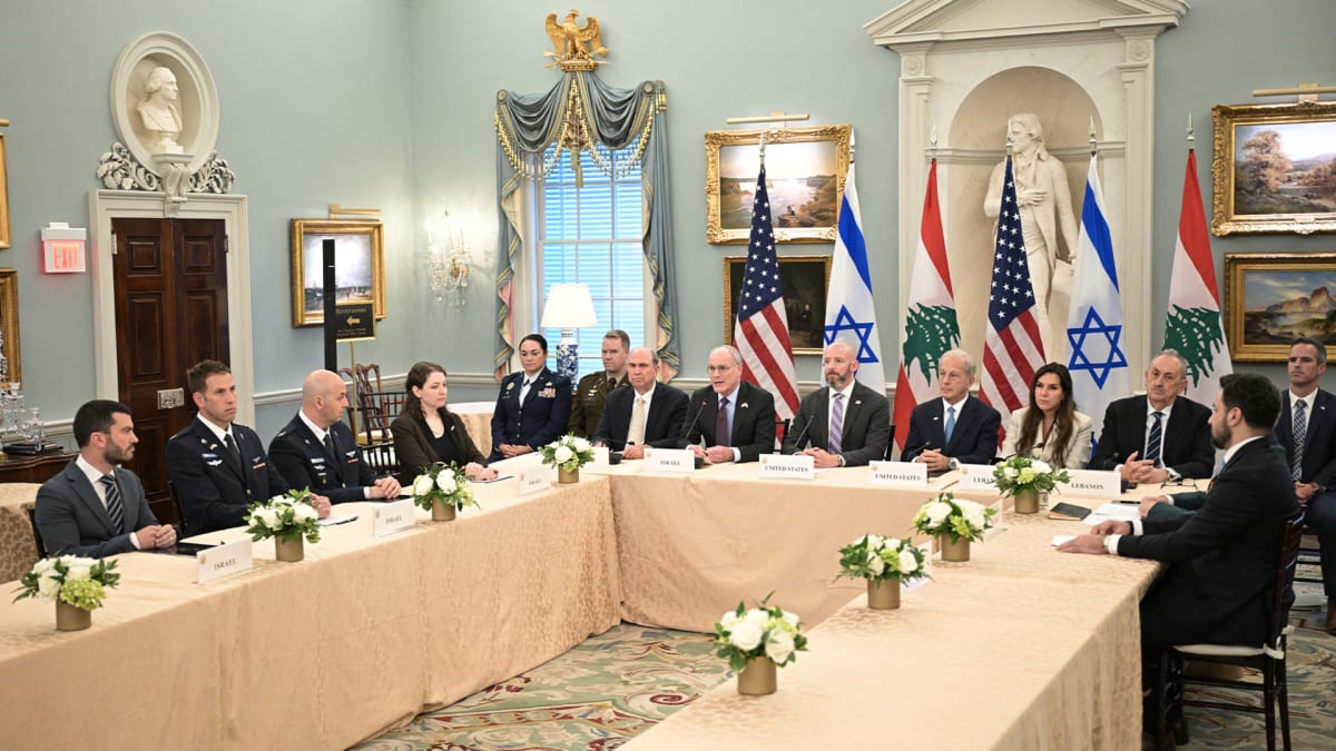 ** Diplomatic officials meeting at negotiation table with Israeli and Lebanese flags displayed