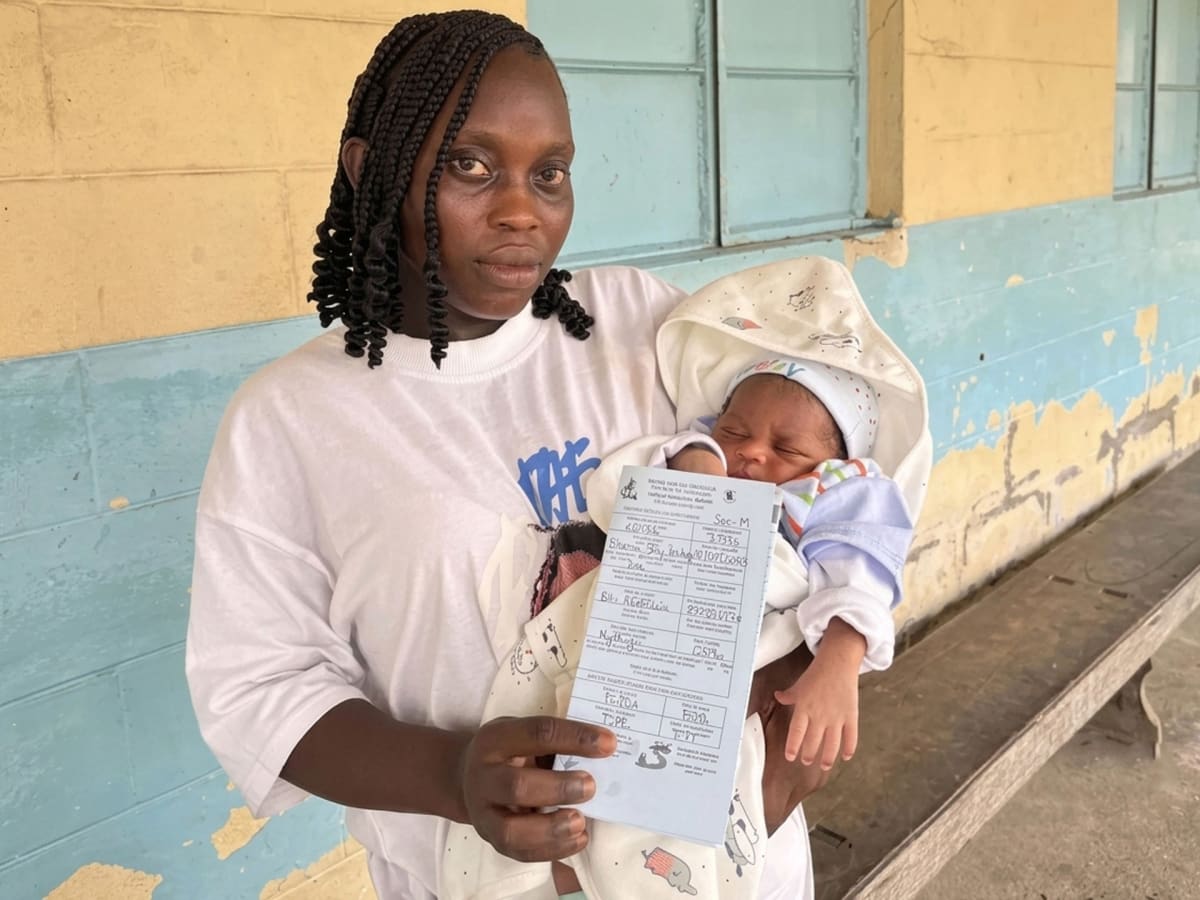 Health worker registering newborn baby while mother holds child in Cameroon hospital
