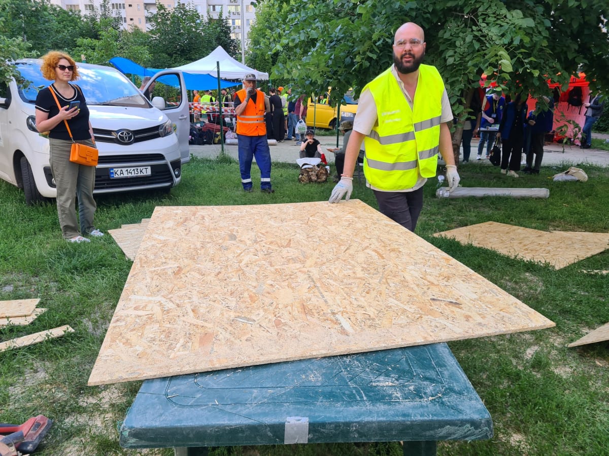 ** International volunteers in orange vests repair shattered windows on damaged Ukrainian apartment building