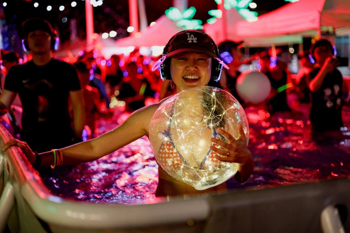 People dancing in pool wearing wireless headphones during Seoul silent disco heat wave party