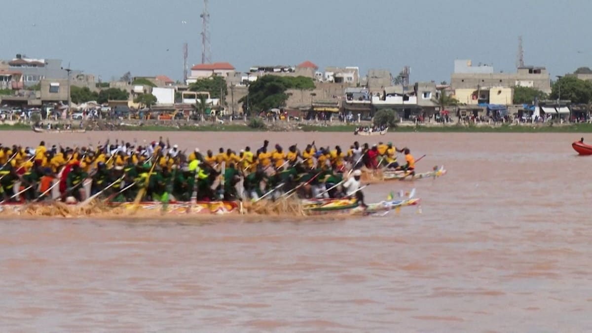 Traditional wooden canoes racing through water during annual Saint-Louis regatta in Senegal