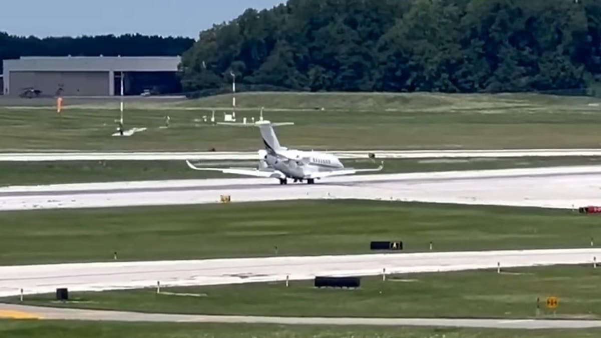 Private jet landing on runway with front nose down and sparks flying from contact point