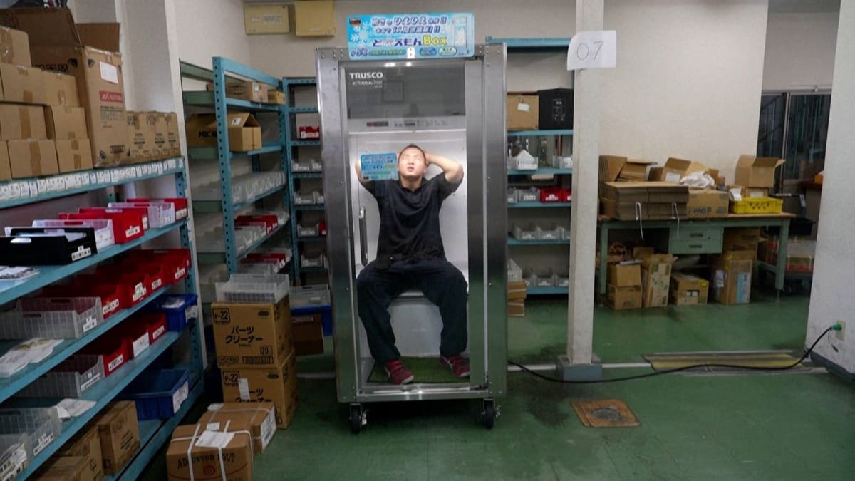 Person entering modern white walk-in cooling booth in Japanese public plaza during summer