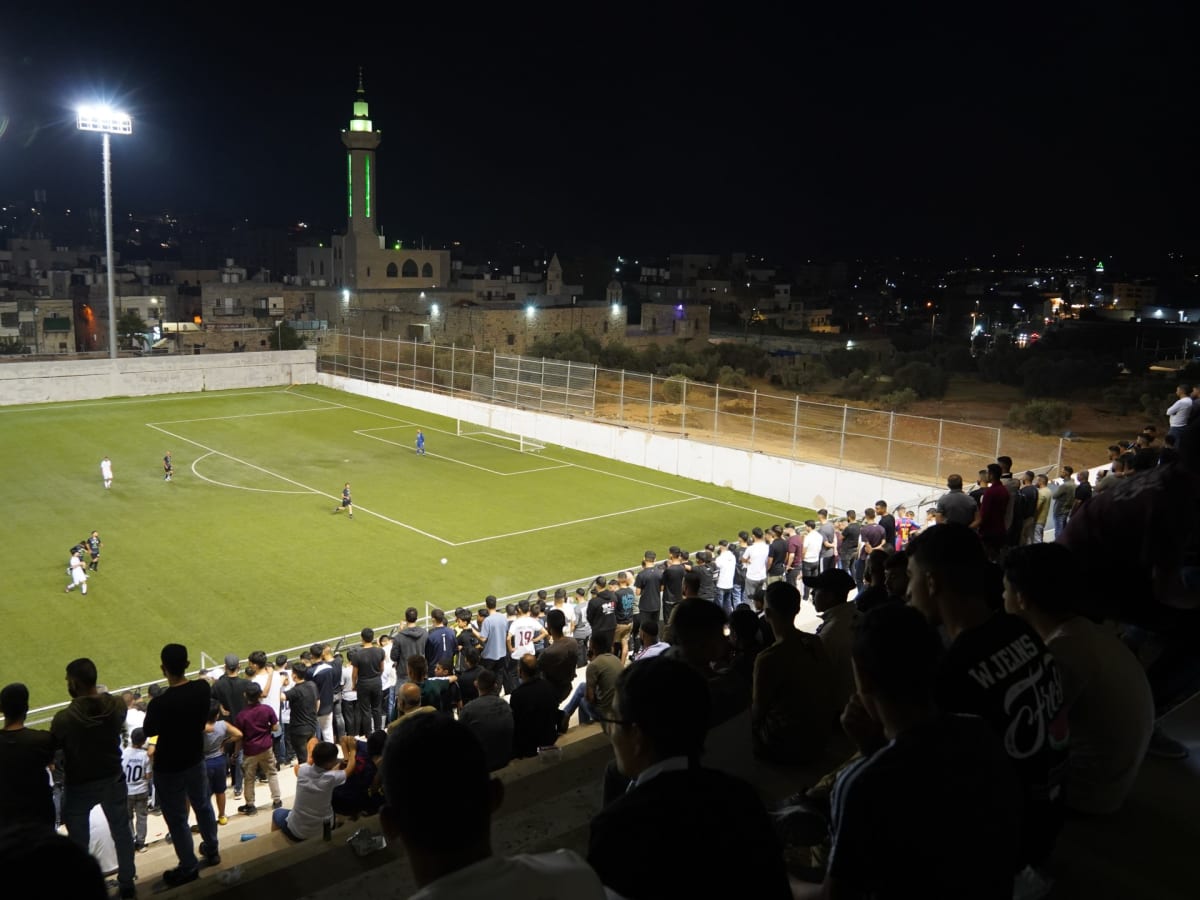 Crowded stadium stands at al-Khader Stadium as Palestinian football fans watch teams compete