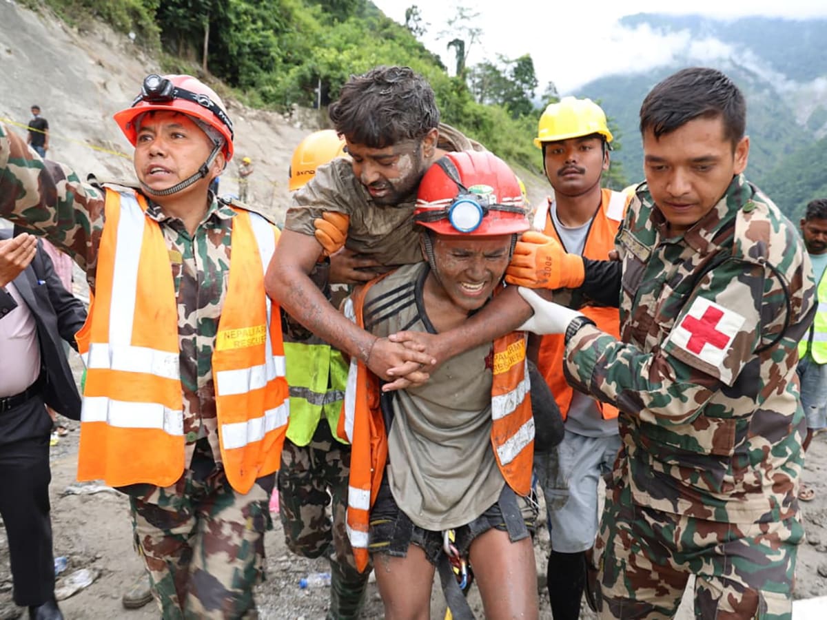** Nepal army rescuers carrying mud-covered worker on stretcher after tunnel rescue operation