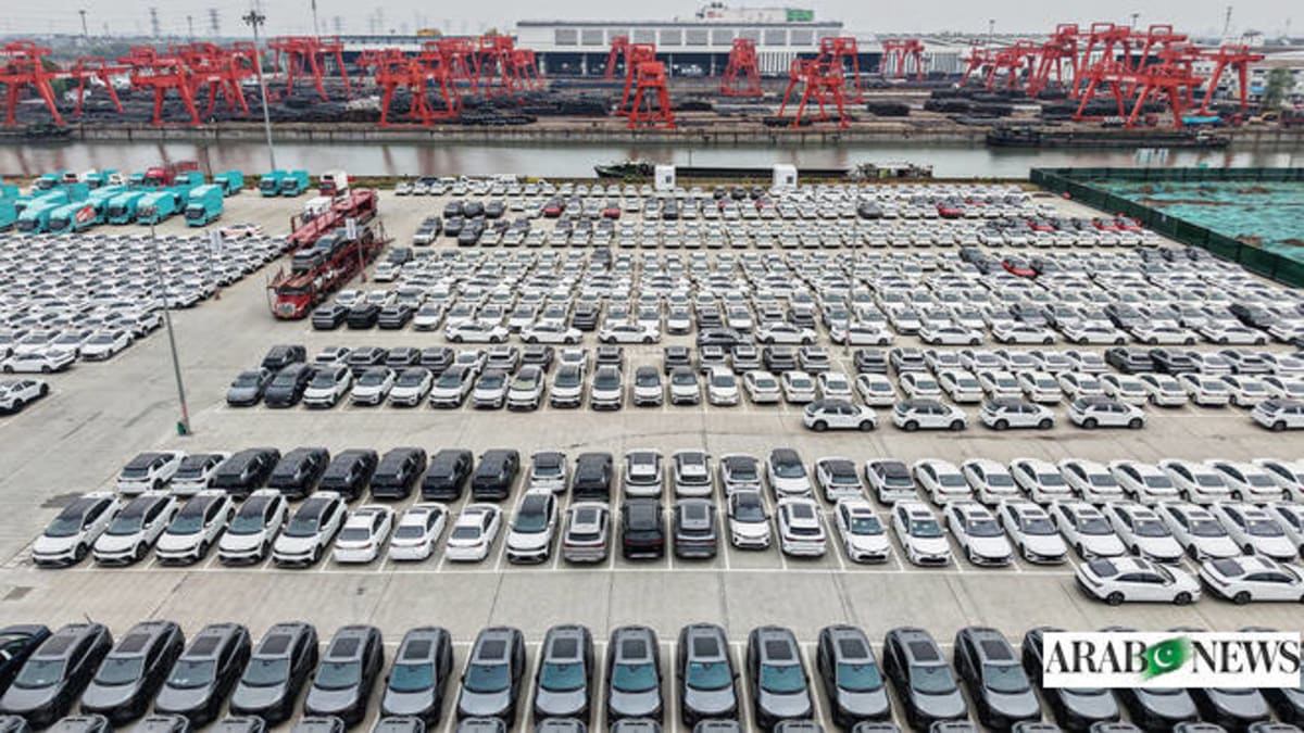Electric vehicles being driven off large cargo ship at modern port terminal facility