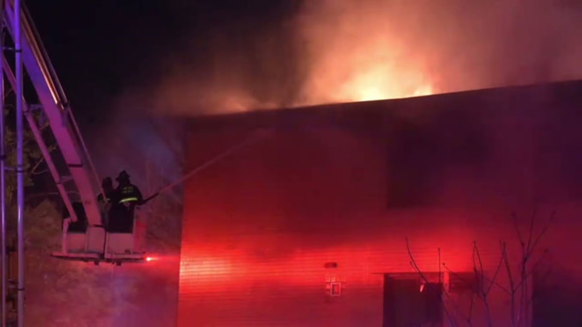 Firefighters climb ladders to rescue residents from burning three-story apartment building at night