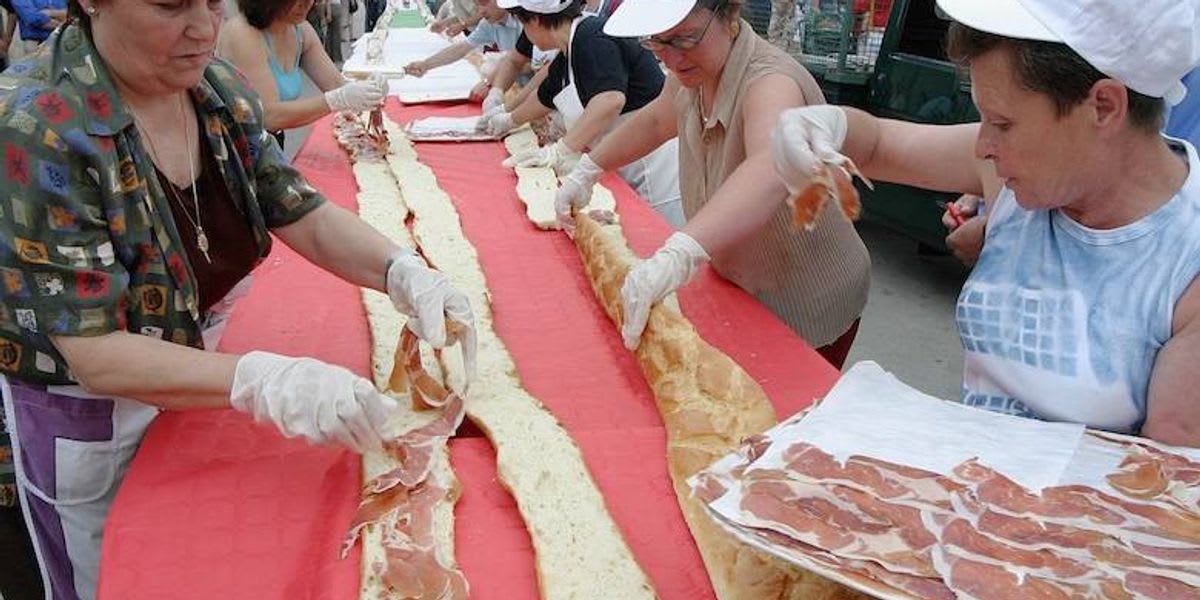 Volunteers assembling sandwiches in a long line at baseball stadium for charity world record attempt