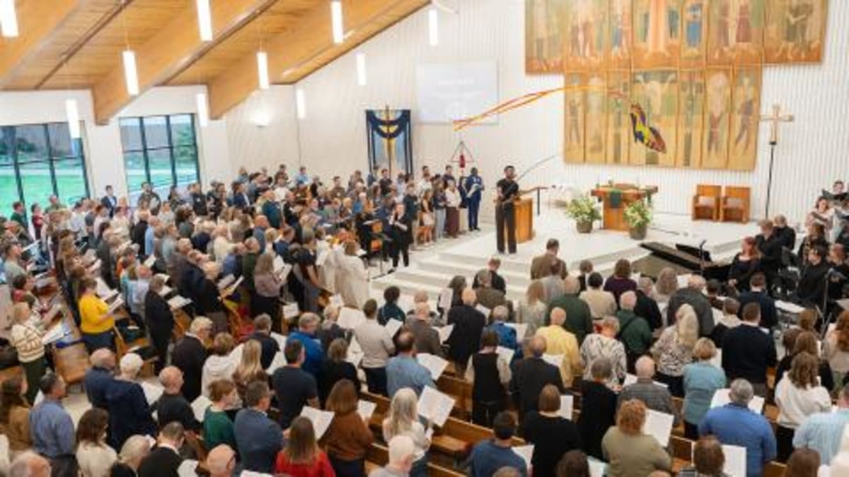 Bright chapel interior with wall of east-facing windows and modern worship seating
