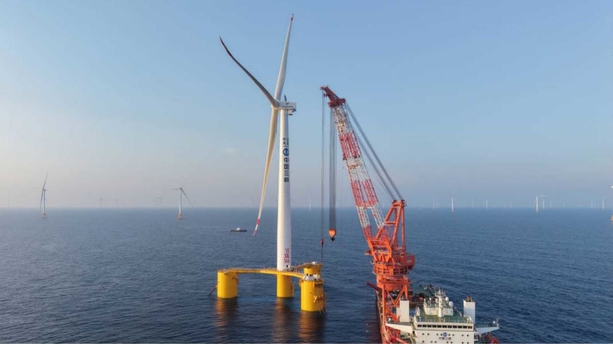 Massive floating wind turbine platform with giant blades towering above ocean water