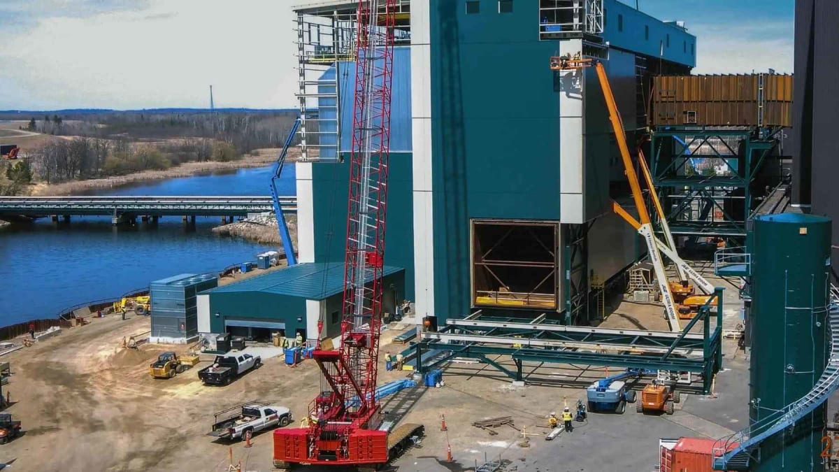 Solar panels on tracking systems beside Minnesota coal power plant cooling towers