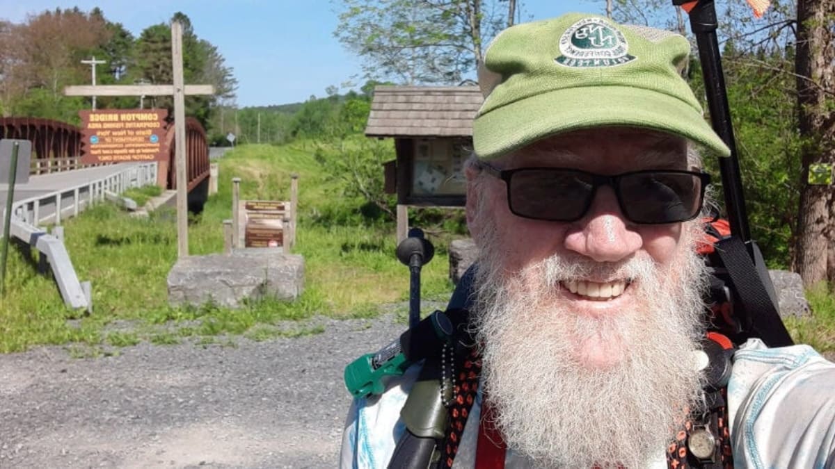 Cancer survivor Tom Walsh hiking on mountain trail with backpack and walking poles