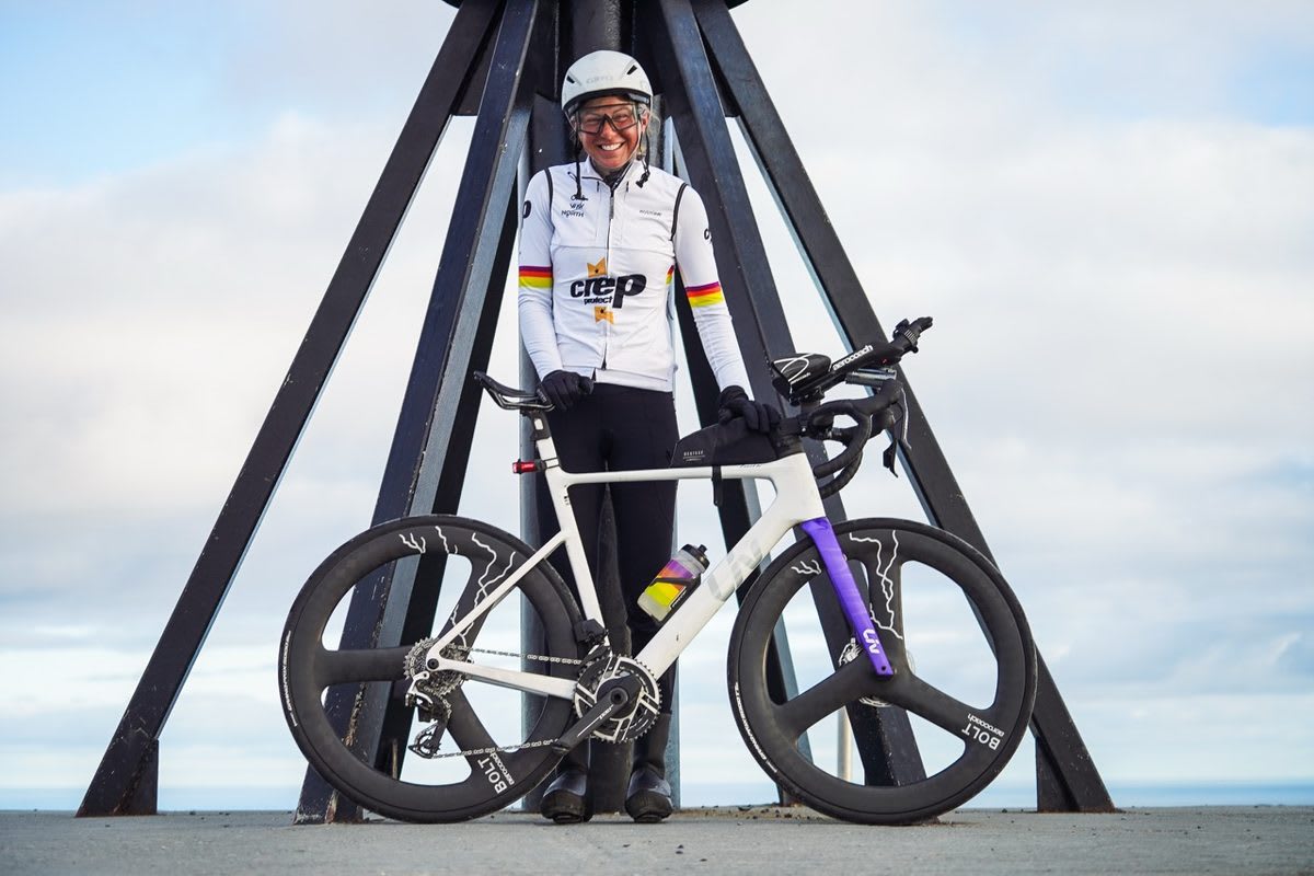 Dr. Sarah Ruggins cycling on road through mountainous terrain during record-breaking Europe journey