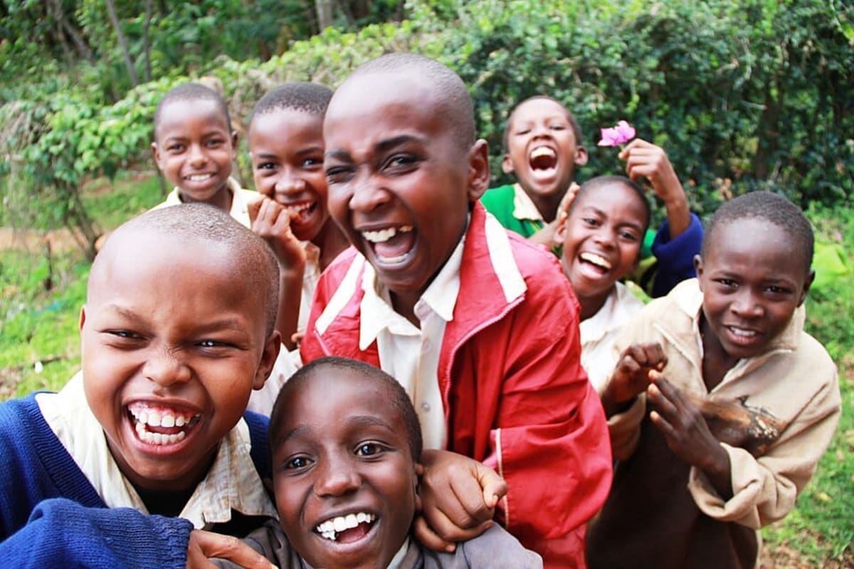 Young Tanzanian students in uniforms sitting at desks in bright classroom studying together