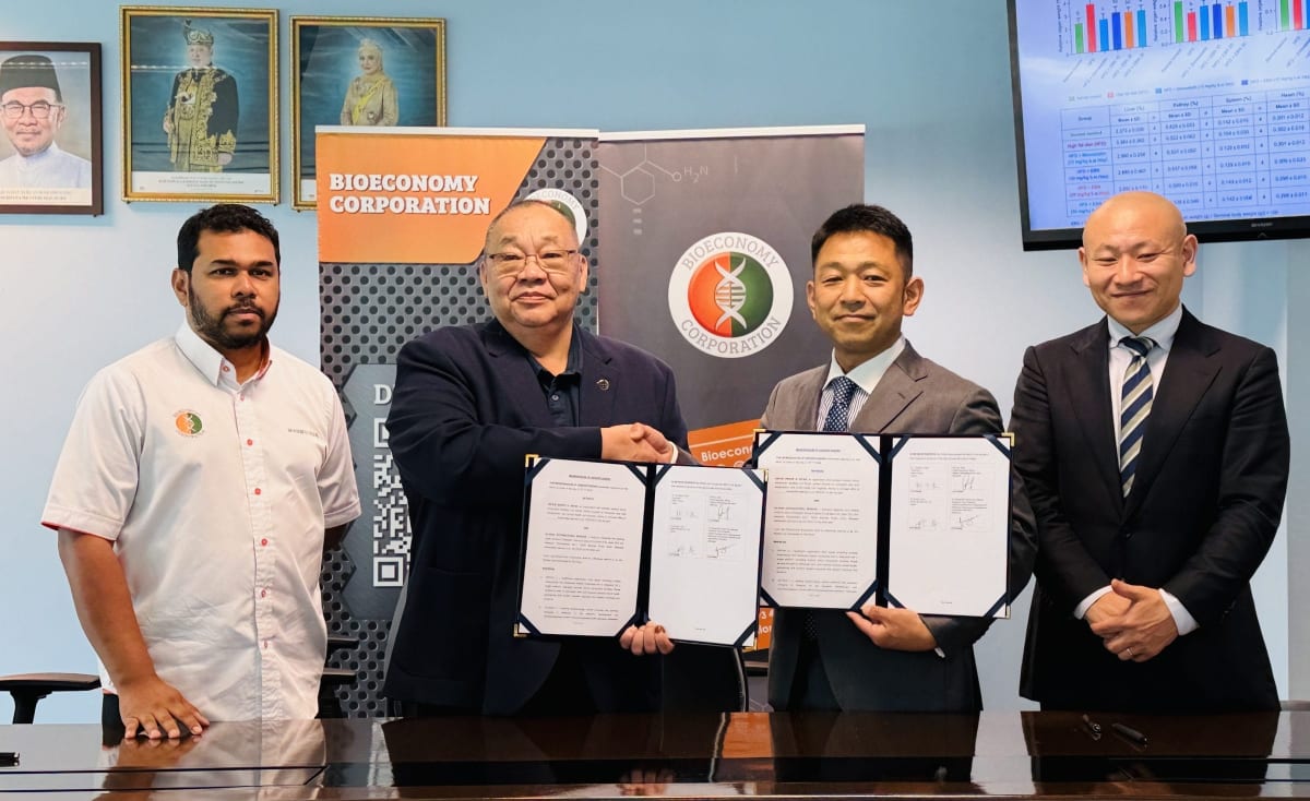 Malaysian and Japanese healthcare executives exchanging collaboration agreement documents for bird's nest medicine research