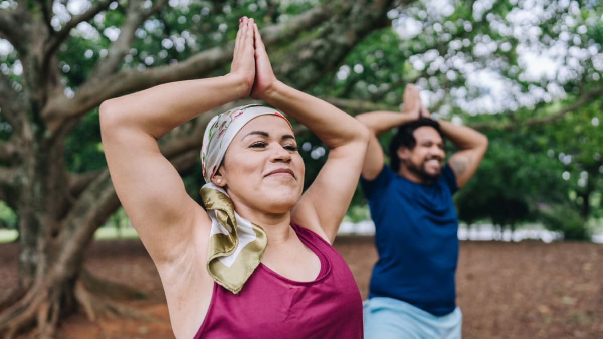 Cancer survivor practicing gentle yoga pose on mat in peaceful indoor setting