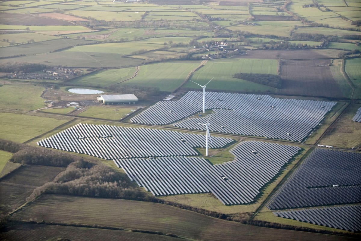 Aerial view of wind turbines and solar farm across green British countryside