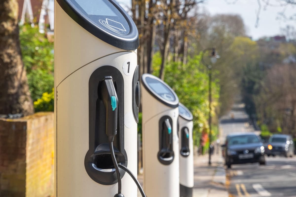 Electric car plugged into charging station on London street with modern buildings in background