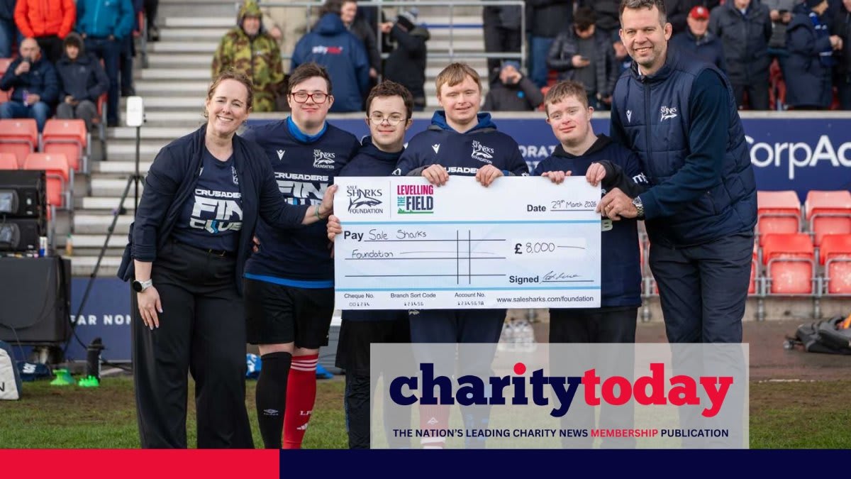 Josh Beaumont presenting large ceremonial check to charity CEO and young rugby players in team uniforms