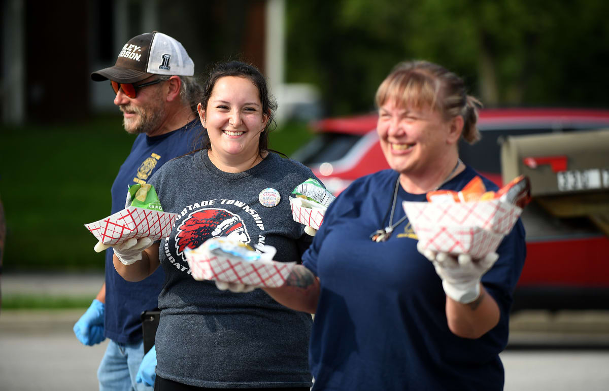 Volunteers holding sandwiches at storm recovery distribution event in Valparaiso, Indiana park